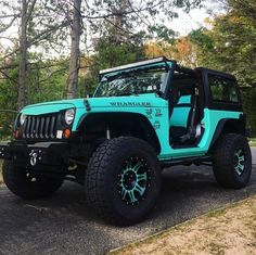 a blue jeep is parked on the side of the road in front of some trees