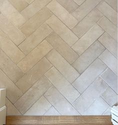 a white toilet sitting next to a wooden floor in front of a wall with a tile pattern on it