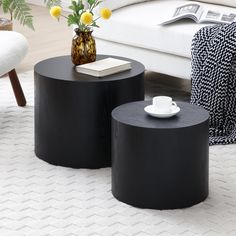 two black tables sitting on top of a white rug in a living room next to a couch