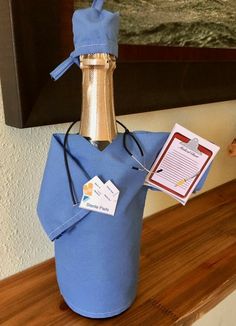 a bottle wrapped in blue paper with a tag on it and a corkscrew