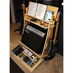 an electronic device is sitting on top of a guitar stand with books and music equipment