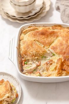 a casserole dish with meat and vegetables in it on a table next to plates