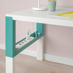 a white table with two plugs on it in front of a pink and blue wall