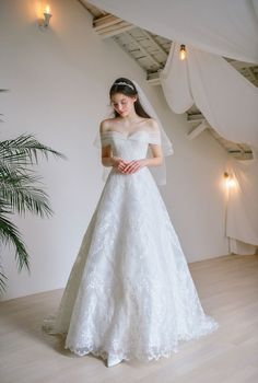 a woman in a white wedding dress standing on a wooden floor next to a plant