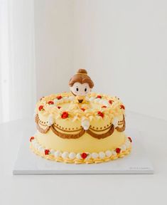 there is a yellow cake with white frosting and a doll sitting on top of it