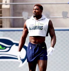 a man with no shirt on standing in front of a football field