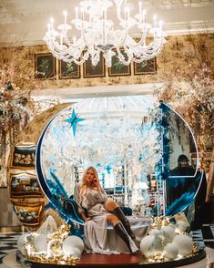 a woman sitting on top of a table next to a chandelier in a store