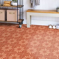 an orange tile floor in a bathroom with shoes on the ground and storage rack behind it