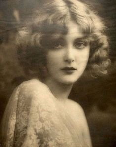 an old photo of a woman with very large breast and short hair, looking at the camera