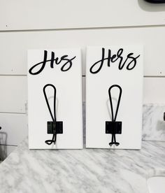 two black and white signs with the words his and hers written on them sitting on a marble counter top