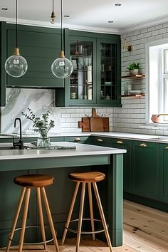 a kitchen with green cabinets and wooden stools next to the counter top, along with two hanging lights