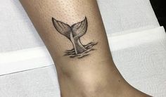 a small tattoo on the leg of a woman's foot with a whale tail