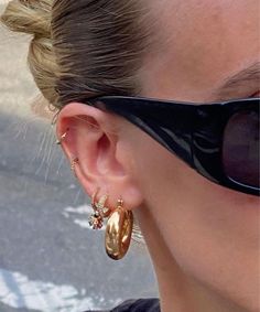 a close up of a person wearing sunglasses and some gold earring designs on their ears