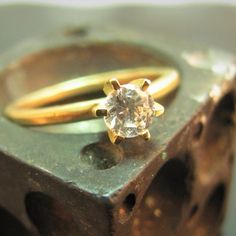 two gold rings sitting on top of a piece of wood with a diamond in the middle