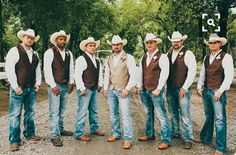 a group of men standing next to each other wearing cowboy hats and vests,