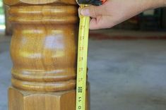 a person measuring the height of a wooden statue with a tape measure on it's arm