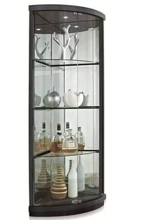 a curved glass display case with bottles and vases on the top shelf in front of it