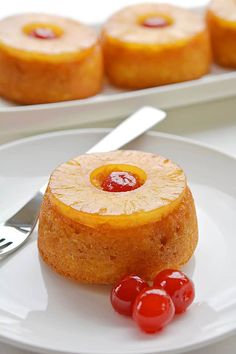 a pineapple upside down cake on a plate with cherries next to the plates