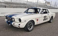 an old race car is parked on the side of the road in front of some bleachers