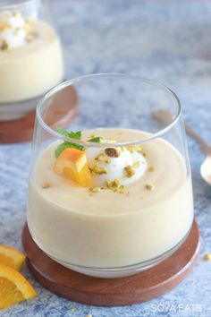 two desserts with orange slices and whipped cream in small glass dishes on a blue tablecloth