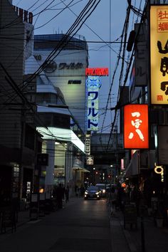 a city street at night with many signs on the buildings