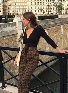 a woman is standing on a bridge with her hands in her pockets and looking at the camera