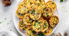 a white plate topped with mini quiche cups next to a fork and knife on a table