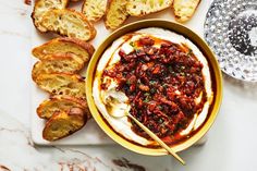 a bowl filled with food next to slices of bread