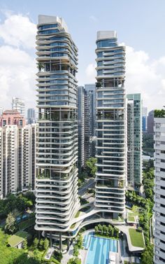 an aerial view of two tall buildings with swimming pool in the foreground and skyscrapers in the background