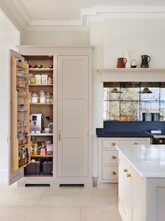 an open cabinet in the middle of a kitchen with lots of counter space and storage