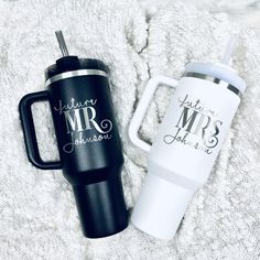 two personalized travel mugs sitting on top of a blanket