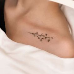 a woman's chest with a small flower tattoo on her left side ribcage