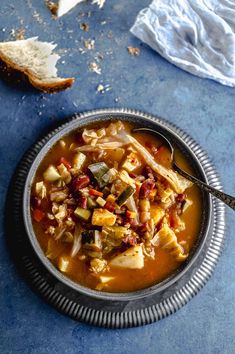 a bowl filled with soup next to bread on top of a blue tablecloth and napkin