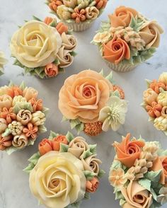 cupcakes decorated with orange and yellow flowers on a marble counter top, ready to be eaten