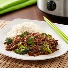 beef and broccoli served with rice on a plate next to a slow cooker