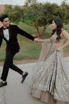 a man and woman dancing on the sidewalk in formal wear, with trees in the background