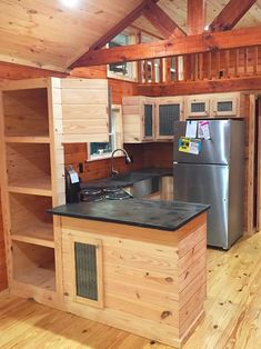 a kitchen with wooden walls and flooring next to a refrigerator