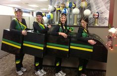 three women in green and yellow uniforms are holding onto some sort of black box with balls on it