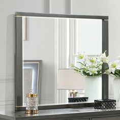 a large mirror sitting on top of a dresser next to a vase filled with flowers