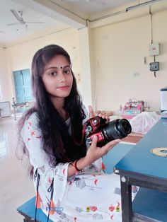 a woman sitting at a table holding a camera