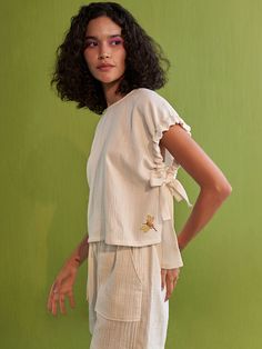 VALUES Handcrafted Organic Fair Minimal Waste CURATOR'S NOTE Relaxed fit, short-sleeve top with ties at the sleeves crafted in double gauge organic cotton fabric, hand embroidered with a dragonfly-inspired motif. This classic, staple top is so versatile and can be endlessly mixed-and-matched to create a fresh outfit each time you put it on. ﻿Techniques Used: Hand Embroidery. THE DESIGNER STORY "Sui" is the new endeavor of the brand Sue Mue. A budding label, that aims to weave together our love f Staple Tops, Classic White Shirt, Fresh Outfits, Bangle Bracelets With Charms, Made Clothing, Organic Cotton Fabric, Brand Collection, Mini Dress Shop, Sustainable Fabrics