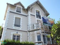 a large white building with a sign on the front and side of it that is being painted