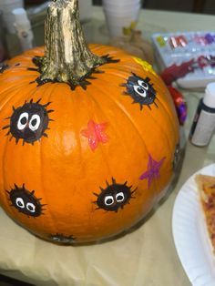 a decorated pumpkin sitting on top of a table next to a slice of pizza with googly eyes