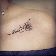 a woman's chest with a flower tattoo on the left side of her breast