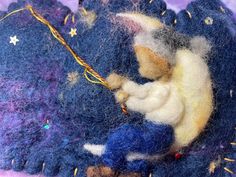 a needled animal laying on top of a pile of blue wool with stars around it