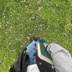 a person standing in the grass with their feet on a book