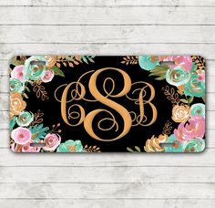 the floral monogrammed door mat is shown in gold and black, with an initial on