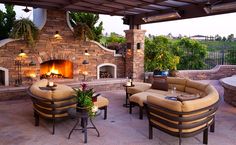 an outdoor living area with couches, chairs and a fire place in the background