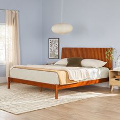 a bed sitting in a bedroom next to a wooden dresser and lamp on top of a hard wood floor