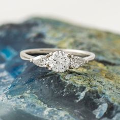 a three stone diamond ring sitting on top of a rock